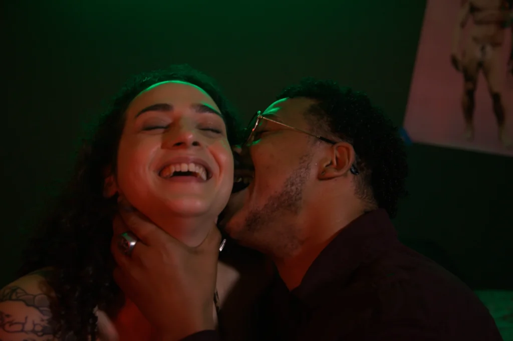 Mulher rindo enquanto o parceiro beija seu pescoço
