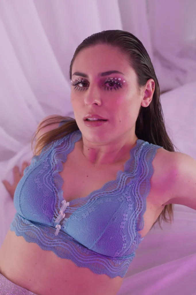Emme White de lingerie lilás em ensaio sobre lençol claro