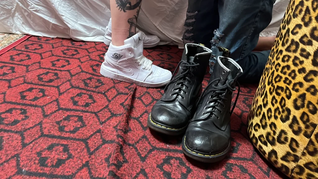 Botas de couro e tênis branco sobre tapete vermelho
